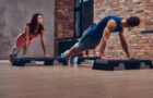 Male fitness coach learning women how to do push ups.